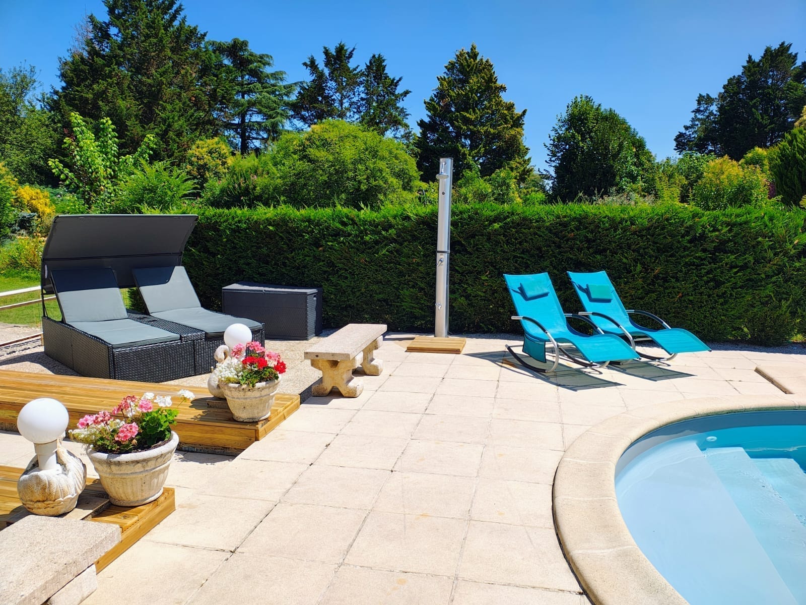 Het zwembad met ligbedden op het terras, omringd door de tuin.