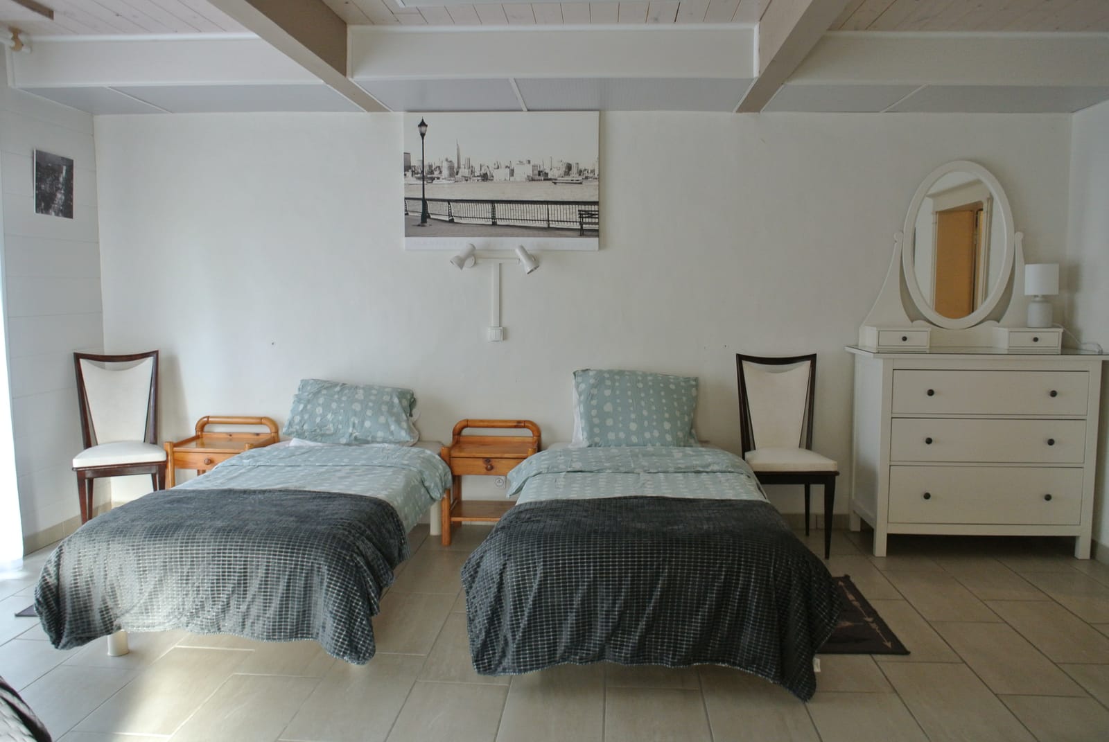 Slaapkamer met twee eenpersoonsbedden en zachtgroene muren.
