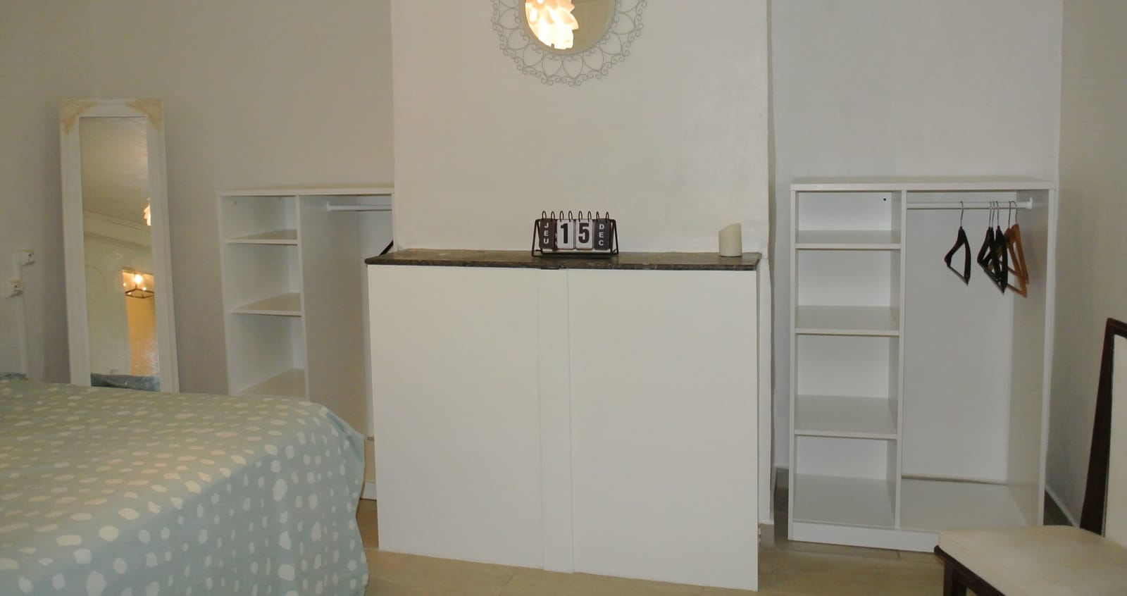 Slaapkamer met tweepersoonsbed, open kasten en garderobe.